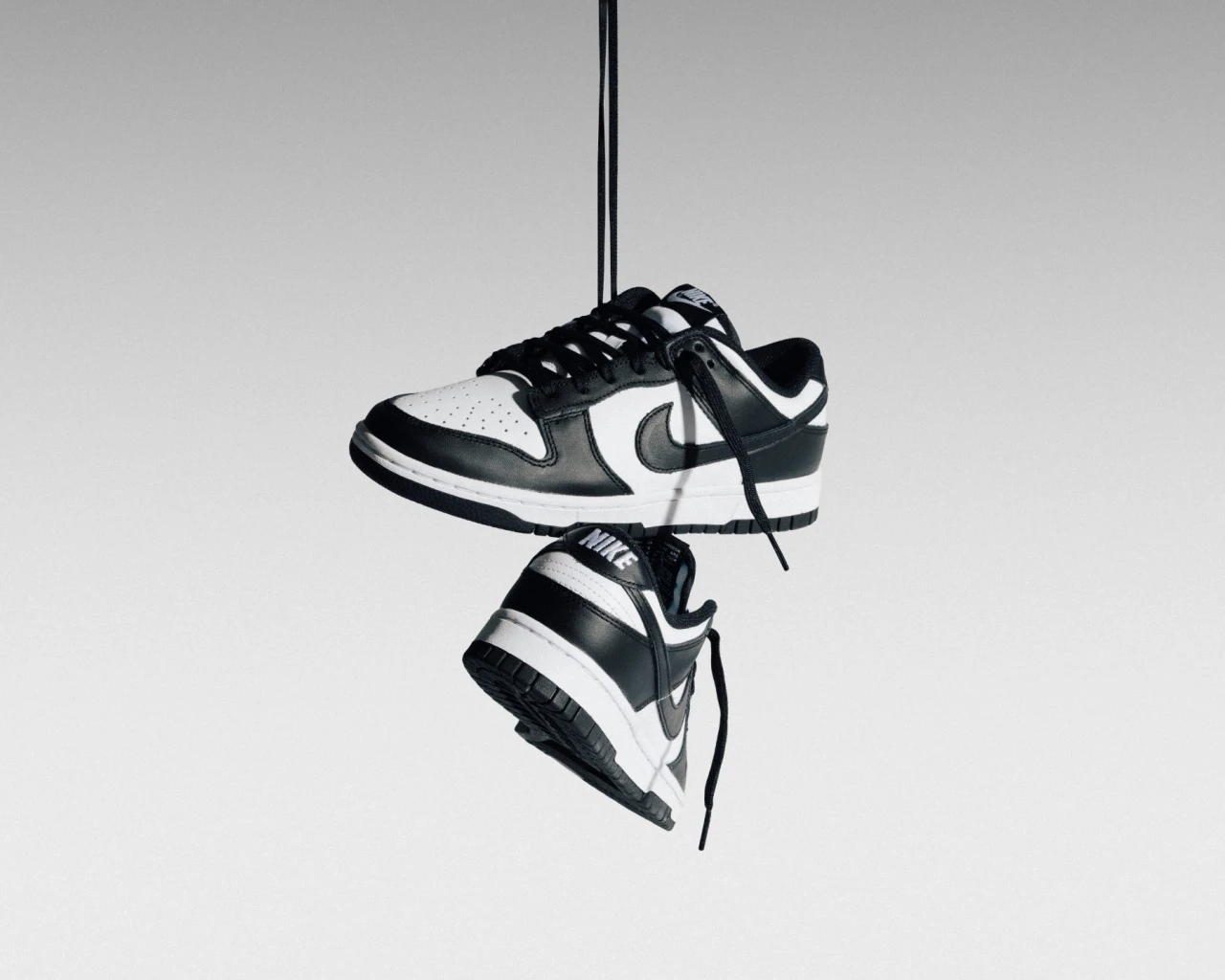 Black and white low-top sneakers suspended against a light background
